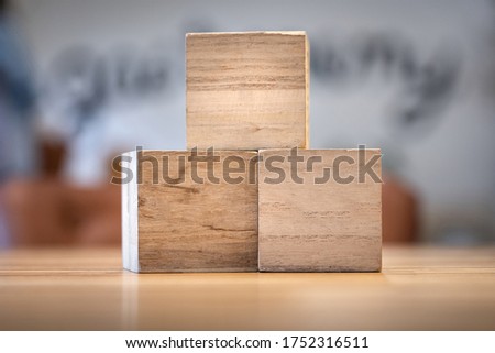 Empty wooden cubic blocks, blank for input text caption or abstract motto on it. Placed on the wooden table with blurred background.