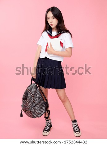 Cute Asian female student on pink background