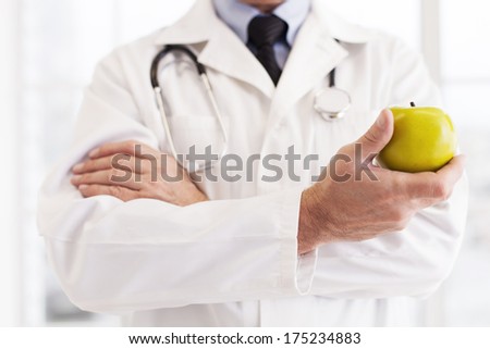 Choose a healthy lifestyle! Cropped image of doctor in white uniform holding an apple