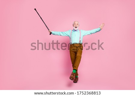 Full body photo of active grandpa moving dance senior party raise up walk stick leg wear mint shirt suspenders bow tie pants shoes green socks isolated pink pastel background Royalty-Free Stock Photo #1752368813