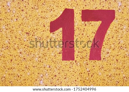 Number seventeen red color painted on a yellow wall with splashes. Royalty-Free Stock Photo #1752404996
