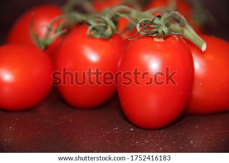 Bright red tomatoes on a branch on a dark surface