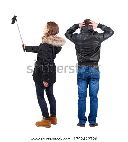 Back view of couple in winter jacket photographed on a mobile phone in winter jacket. beautiful friendly girl and guy together. Rear view people collection. Isolated over white background.