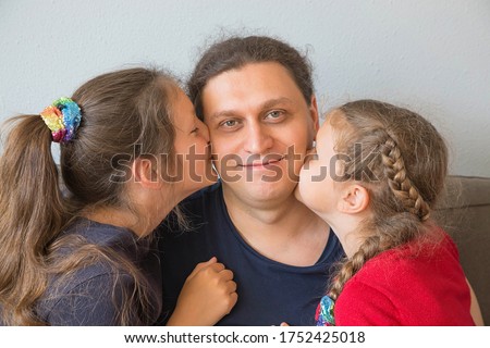 Children kiss father. Two little girls kiss dad on both cheeks. Father day concept.