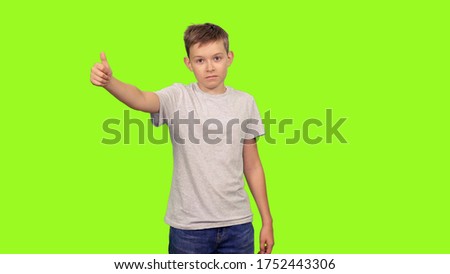 Portrait of teenage boy showing thumb up signs on green screen background, Chroma key