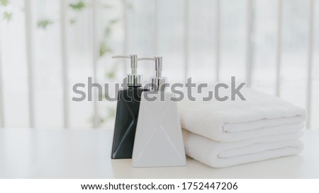 Shampoo and shower cream bottle with laundry white towel in bathroom with copy space.