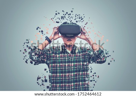  Asian man wearing glasses of virtual reality dissolving into pixels is touching on gray background Future Technology Concept