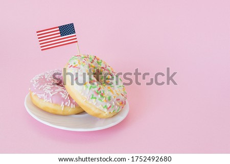 Little american flag stuck in donuts on pink background. 4th of july, usa independence day. Celebration memorial day in America. Copy space for text.
