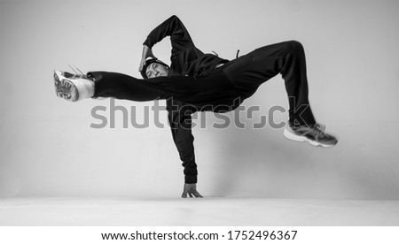 A man hip hop dancer or bboy freezes in one pose on a white background. Bboy doing stylish stunts. Royalty-Free Stock Photo #1752496367