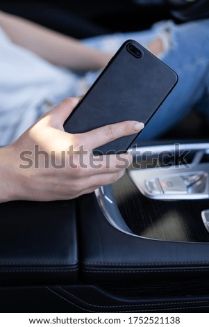 Girl holding phone in hands while sitting in the car. vertical photo