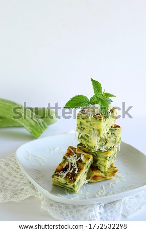 Spring food concept. Homemade zucchini and leek frittata fingers sprinkled with parmesan, mint flavor. Closeup. White background.