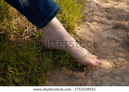 womans leg on the green grass and sand
