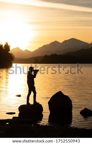 Silhouette of a male photographer during sunset with a lake and mountains in the background, Patagonia Argentina