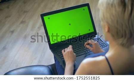 chroma key on laptop screen. look over your shoulder. woman uses laptop at home.