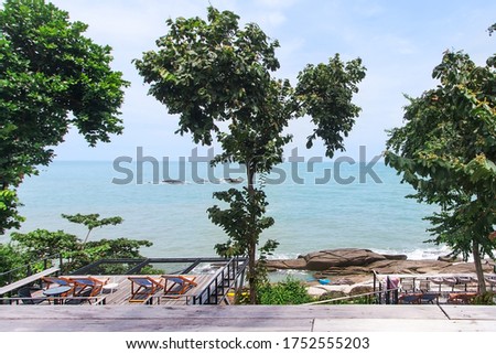 Relaxing spot and viewpoint on the beach With large stones With green trees On a day with turquoise waters and clear skies and beautiful clouds. the picture is partially clear.