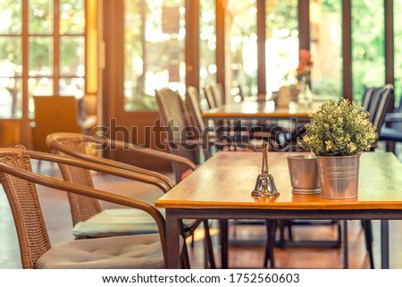 A small bell for calling the waiter and artificial flowers in an aluminum pot placed on a table in a coffee shop. Royalty-Free Stock Photo #1752560603