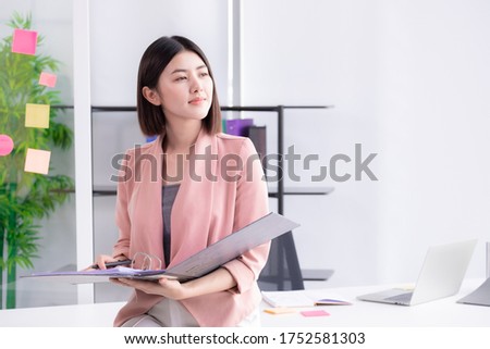 Young Asian businesswoman holding folder and look report document in side.
