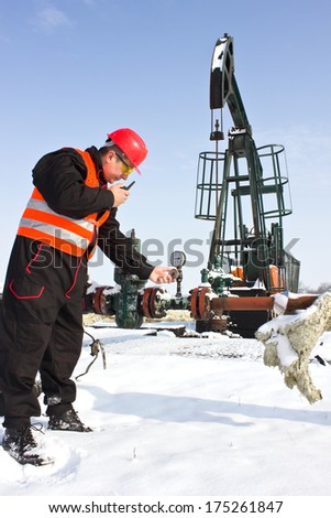worker on an oil pump pressure gauge reading and speaking in a radio station, best focus pump, soft focus man