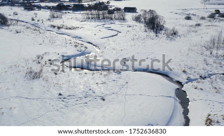 Flying in winter over a swamp covered with forest. Small river in the snow, Aerial View  