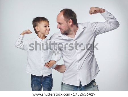 dad and son show the strength of their biceps. fatherhood, psychology of relationships.Studio, White back Royalty-Free Stock Photo #1752656429