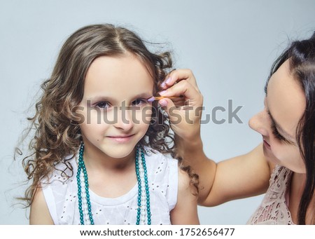 mother puts makeup on her little daughter. photo session in the Studio on a white back