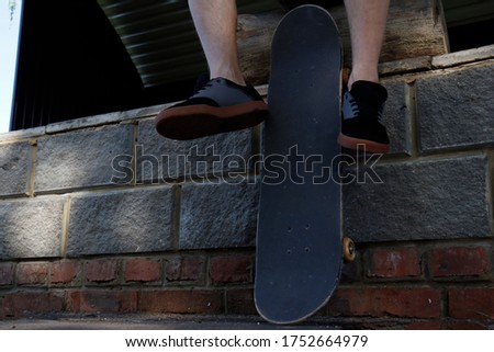 hipster with skate sitting dangling legs, young skater