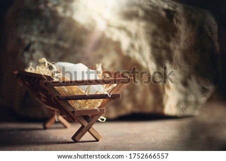 Christian Christmas concept. Birth of Jesus Christ. Wooden manger in cave background. Banner, copy space. Nativity scene symbol. Jesus is reason for season. Salvation, Messiah, Emmanuel, God with us