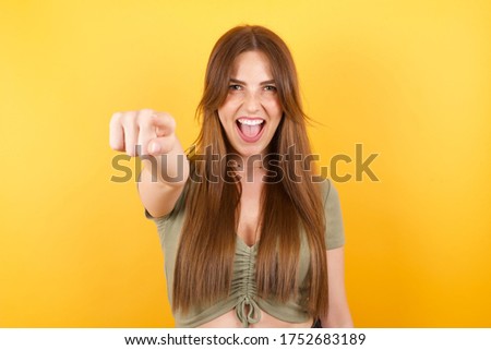 Young caucasian woman with long hair wearing green tshirt pointing displeased and frustrated to the camera, angry and furious ready to fight with you.