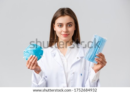 Covid-19, preventing virus, healthcare workers concept. Professional attractive female doctor in scrubs, advice using protection to prevent coronavirus outbreak, show respirator and medical mask