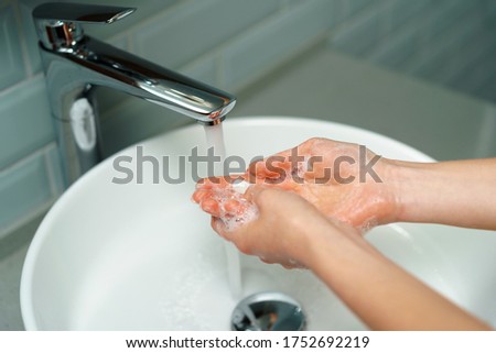 Close up of a woman washing her hands in a bathroom sink