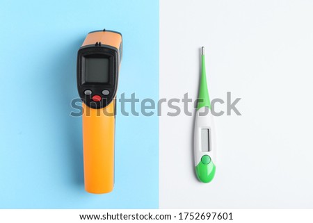 Non-contact infrared and digital thermometers on color background, flat lay