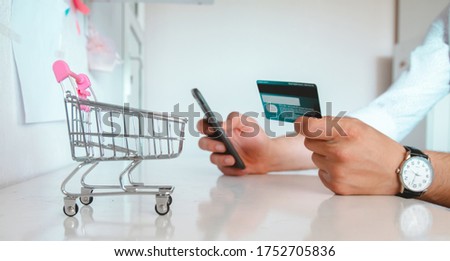 young man shopping online with phone and credit card in his hand