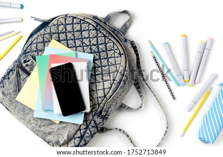 Flat lay top view backpack with different colorful stationery on white table. Back to school concept