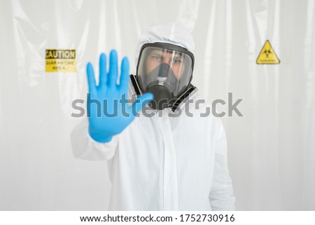Portrait of doctor in medical uniform with a protective face mask and a gloved hand showing a stop sign. Stop COVID-19 concept.  The epidemic of coronavirus.