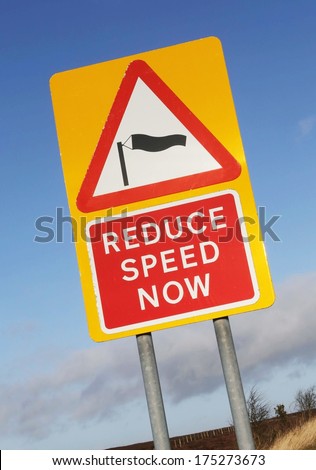 Sudden side cross winds likely ahead road sign, isolated traffic warning flying sock crosswinds sidewind signage with a Reduce Speed Now instruction.
