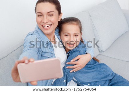 Mother daughter testing new face app on mobile phone. Have fun together take selfies pictures photo. Posing smile hug enjoy time on weekend holiday. Adult Sister hold cell laugh widely. Pastel cute