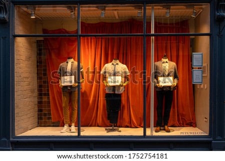 Mannequins in a shop front window holding signs showing messages of support
