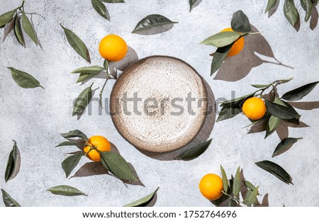 Whole oranges witl orange tree leaves on white background around empty plate. top view, flat lay, summer and healthy concept. Mockup