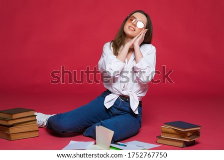 Image of surprised positive young woman isolated over red wall background holding notebook.