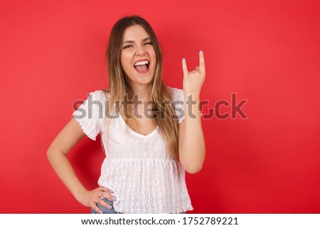 Portrait of a crazy girl showing tongue horns up gesture, expressing excitement of being on concert of band.