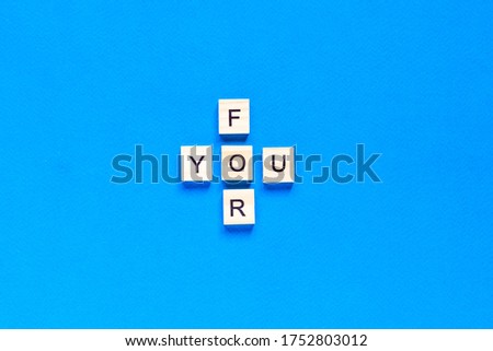 FOR YOU written in wooden letters on a blue background. top view, flat layout.