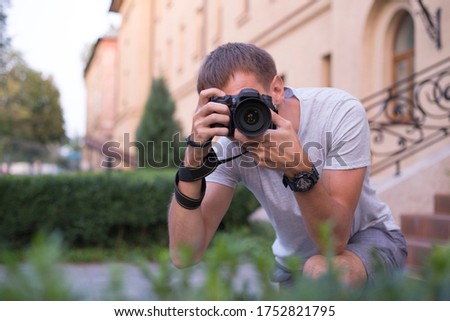 Faceless young man with a digital SLR camera who takes pictures in the park