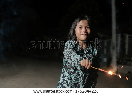 Malay girl celebrating Hari Raya Aidilfitri playing firework in hand