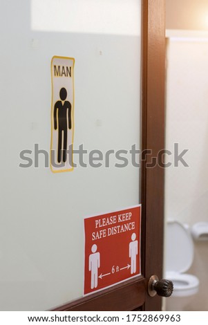 Red sign PLEASE KEEP SAFE DISTANCE 6 ft  on Public men toilet door. New normal that people need to keep social distance to prevent and protect from virus spread. Social distancing in the toilet.