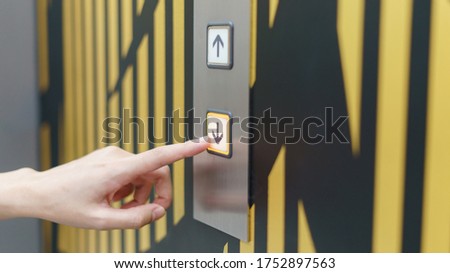 Woman finger pressing a down button of elevator button inside the building. 