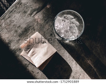mash ice in the clear glass on cement table. And  a napkin beside this clear glass.
