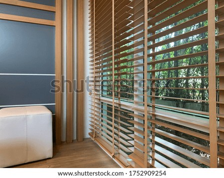 The living room corner has wooden blinds for blocking the light from the outside.