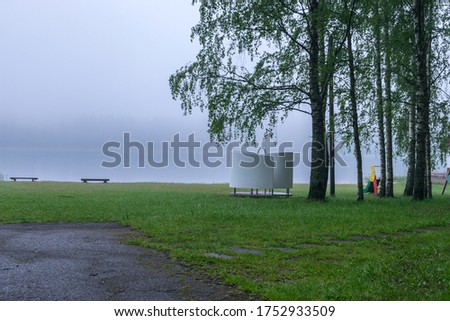 mystical fog picture on an empty beach early in the morning, blurred misty lake background