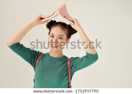 I'm home. Closeup photo of pretty funny lady hold open book homework under head fooling around childish mood isolated light background