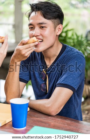 Asian Portrait asian Man students eating pizza with cheese delicious at outdoor university, Education concept
